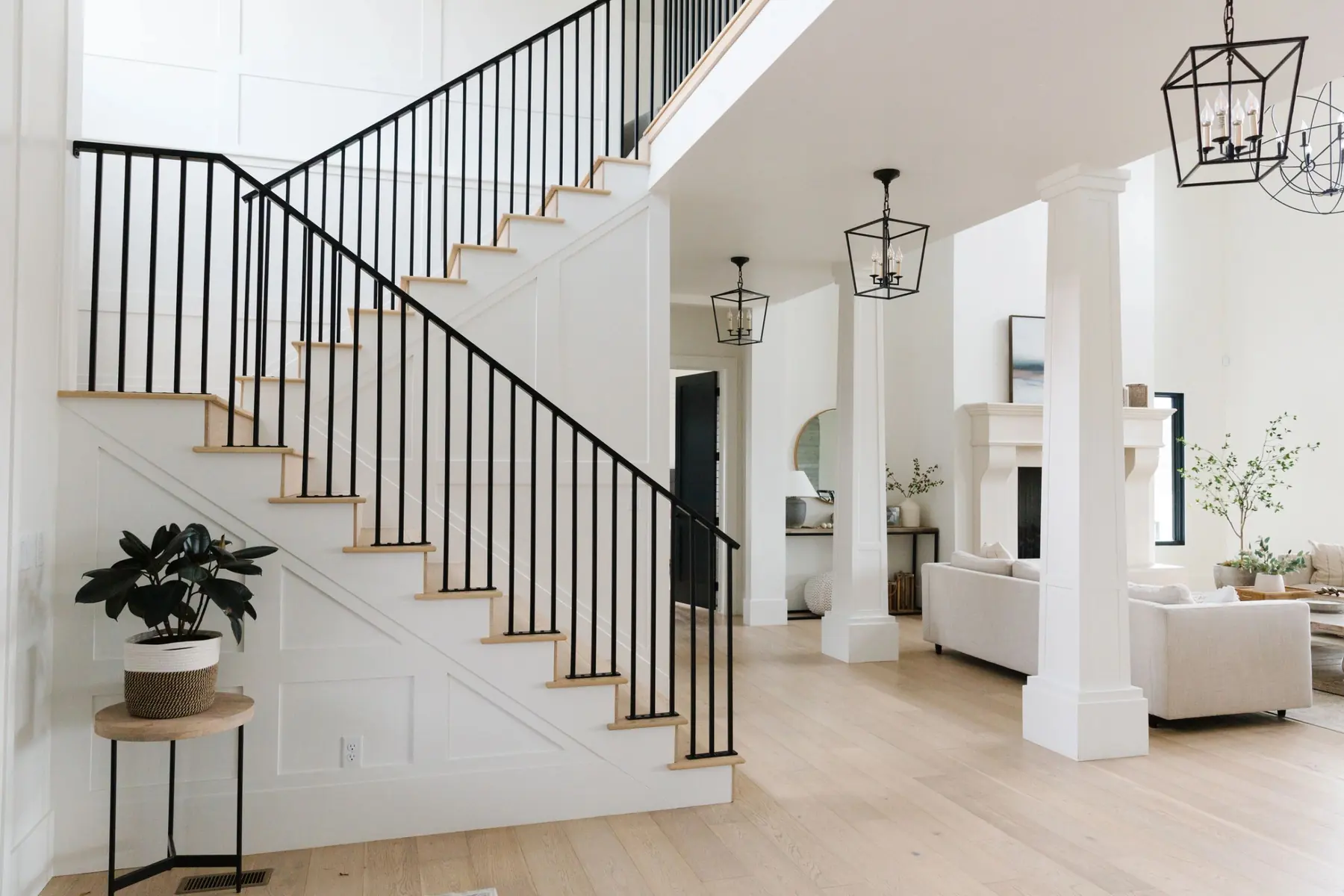 Staircase with black iron railing and a bright living room beyond