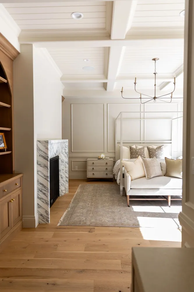 A bedroom with built-in shelving, paneling and warm wood floors